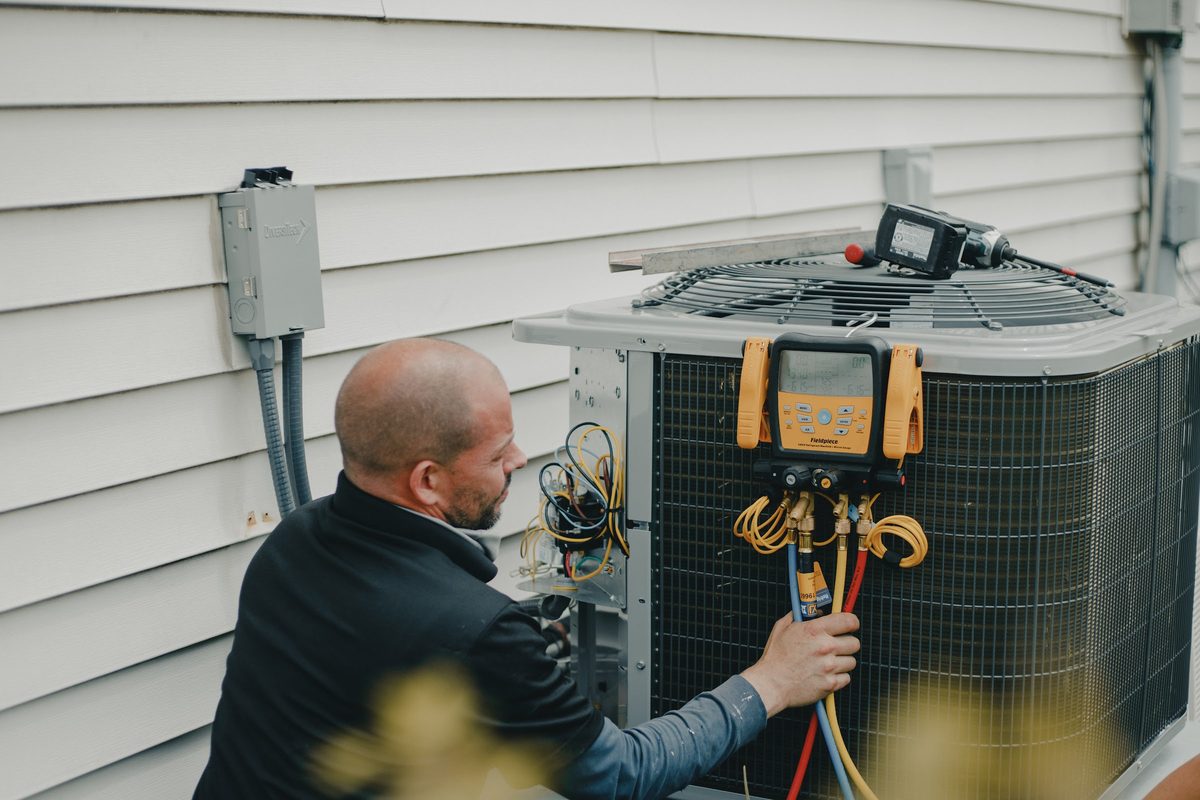 Topline technician commissioning a new outdoor HVAC unit with a digital refrigerant manifold gauge