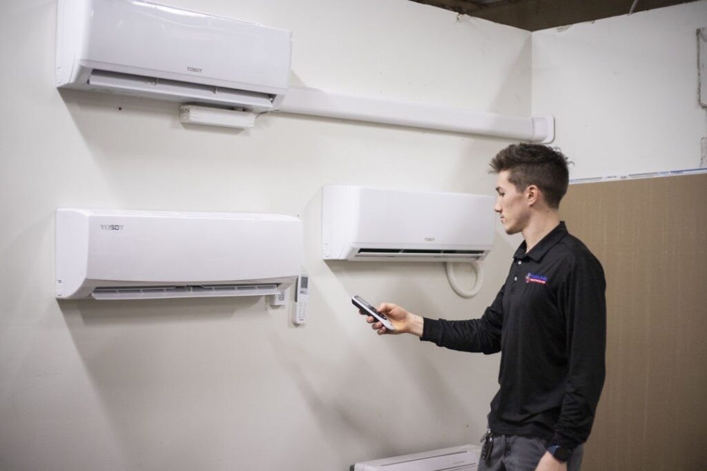 Topline technician using a remote to control wall-mounted ductless mini-split indoor units